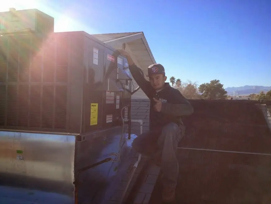 HVAC technician performing Air Duct Cleaning on a rooftop unit in Dickinson
